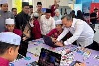 Anuar Fariz (kanan) beramah mesra dengan pelajar pada Majlis Penyerahan Digital Maker Hub kepada pengurusan Pondok Darul Furqan pada Isnin.
