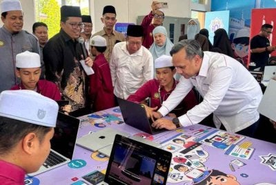 Anuar Fariz (kanan) beramah mesra dengan pelajar pada Majlis Penyerahan Digital Maker Hub kepada pengurusan Pondok Darul Furqan pada Isnin.