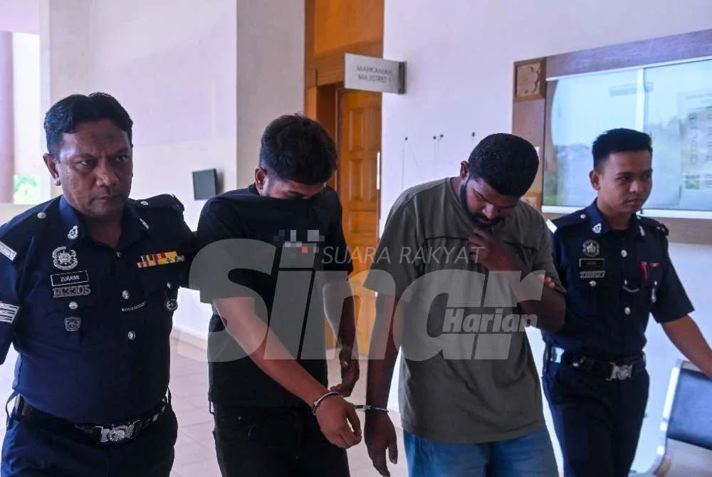 Anggota polis mengiringi keluar Guna (kanan) dan Mohd Sharuf Nizam selepas selesai sebutan kes dalam Mahkamah Majistret Kuantan pada Rabu.