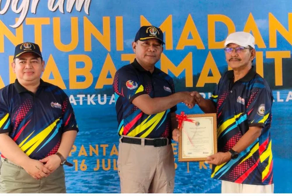 Mohd Rosli menyampaikan sijil pelantikan Sahabat Maritim kepada wakil penduduk sempena sempena Program Santuni Madani dan Sahabat Maritim di Pantai Rekreasi Balok di sini pada Khamis.