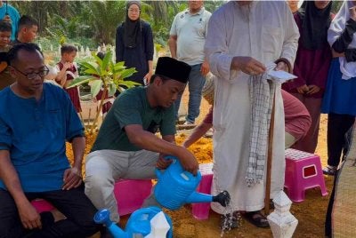 Mohd Faaiz (dua dari kiri) sebak ketika pengebumian anaknya di Tanah Perkuburan Islam Sri Lalang, Kluang.