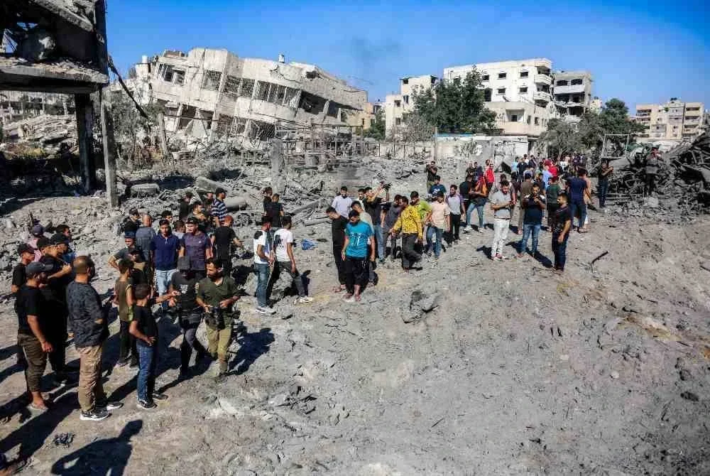 Penduduk Palestin melintasi runtuhan bangunan yang musnah akibat serangan Israel. Foto AFP