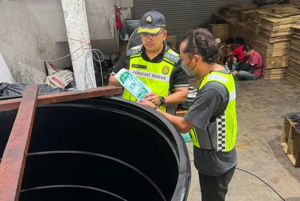 Penguat kuasa KPDN memeriksa lokasi serbuan.