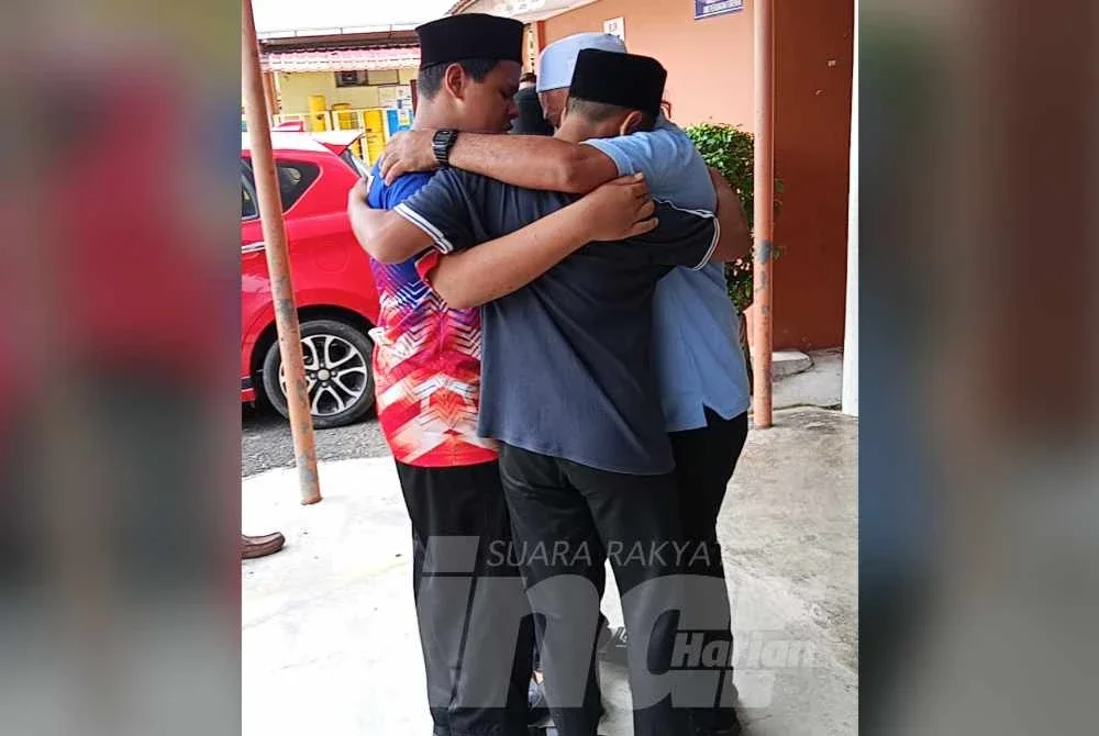 Kamaruzaman memeluk rakan-rakan arwah anaknya di luar Unit Forensik Hospital Kota Tinggi.