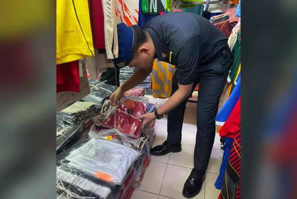 Pegawai KPDN Johor memeriksa jersi tiruan yang dirampas dalam operasi penguatkuasaan. Foto KPDN Johor