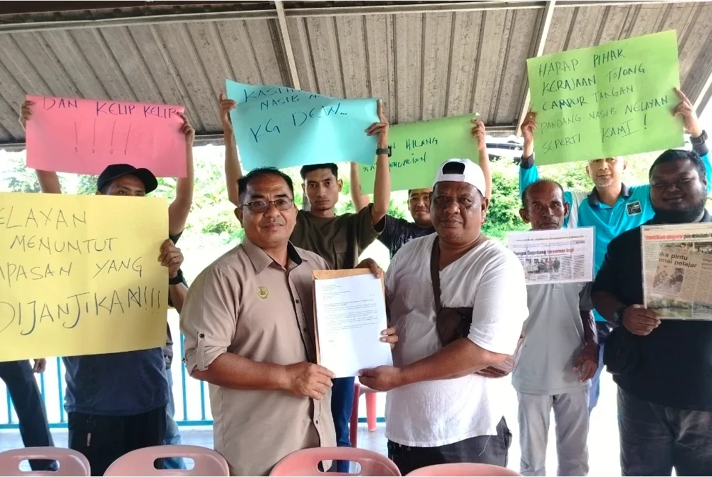Shukor (kanan) menyerahkan memorandum kepada Muhammad Hanafi bagi meminta kerajaan negeri mengambil tindakan sewajarnya untuk membela nasib nelayan di kawasan terbabit.