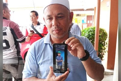 Kamaruzaman menunjukkan gambar arwah anaknya.