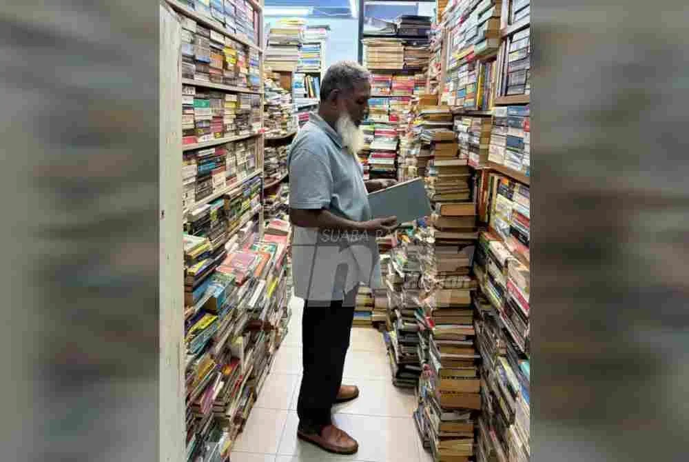 Seorang pemilik kedai buku terpakai di Chowrasta memeriksa koleksi buku di premisnya yang terus menjadi destinasi pencinta buku sejak puluhan tahun lalu.