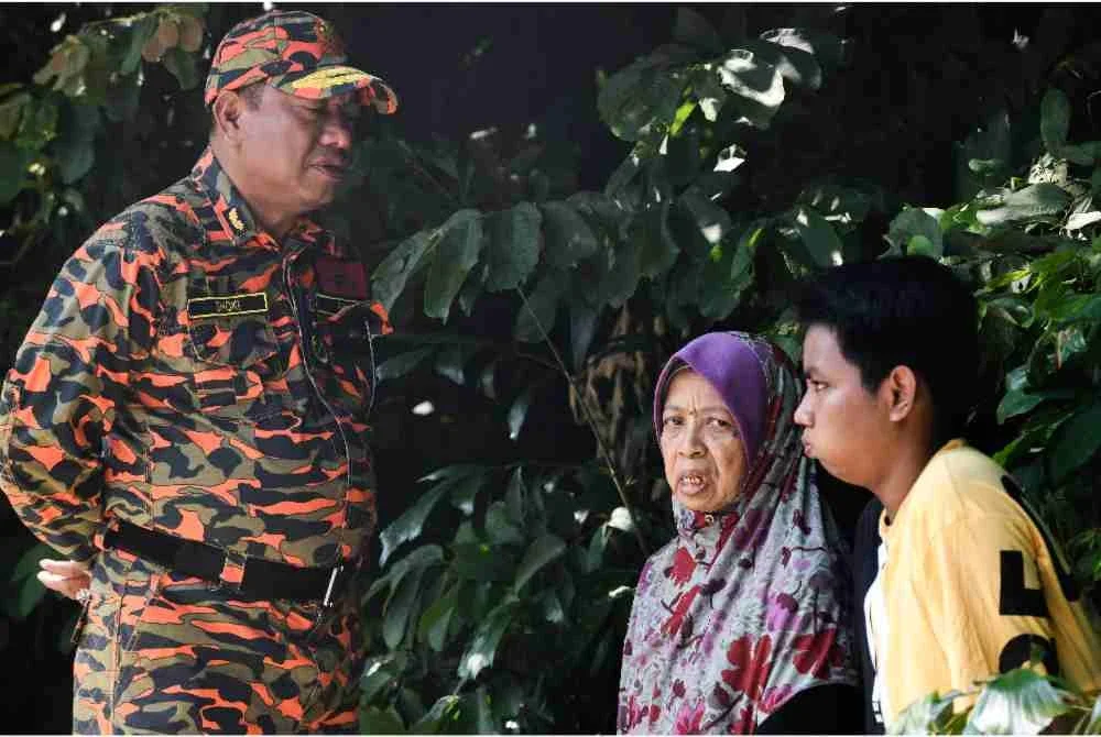Pengarah Jabatan Bomba dan Penyelamat Malaysia (JBPM) Pulau Pinang, Mohamad Shoki Hamzah bersama ibu mangsa Shahir Zainul, Salmah Shamsudin, 72, dan anak mangsanya, Muhammad Ali Imran, 15, semasa operasi mencari dan menyelamat (SAR) bagi mengesan Shahir Zainul, 45, yang dilaporkan hilang selepas keluar dari rumahnya di Persiaran Mayang Pasir 2, Bayan Baru dekat sini, sejak 10 Jun lepas. Foto Bernama.