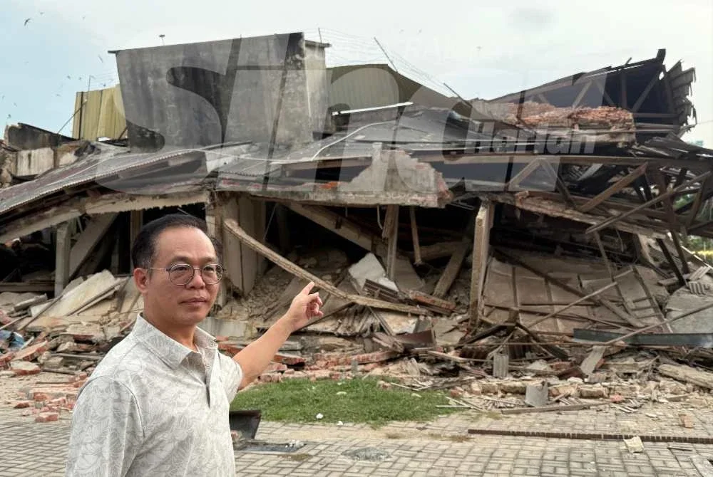 Chee Leong menunjukkan bangunan rumah kedai yang runtuh dalam kejadian Sabtu