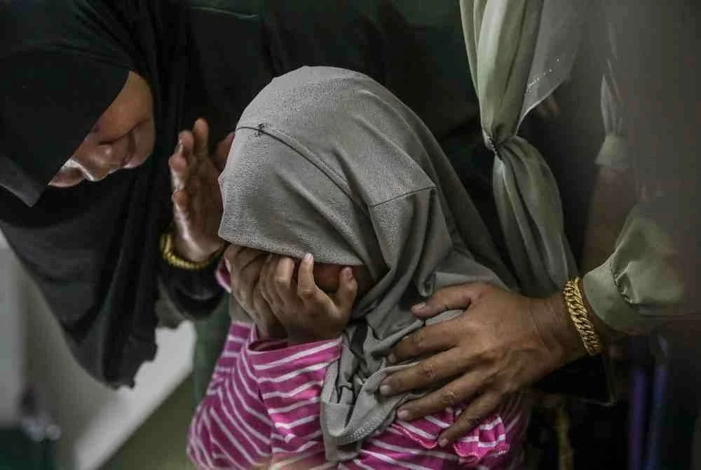 Ahli keluarga dan orang ramai sebak melihat jenazah Nur Atikah Abdullah, 28, dan sepupunya Muhammad Aariz Daniel, 3, yang terkorban dalam kejadian fenomena kepala air di Sungai Sedim, Kulim, semalam, di Tanah Perkuburan Islam Kampung Palas, Kangar, hari ini. Foto Bernama