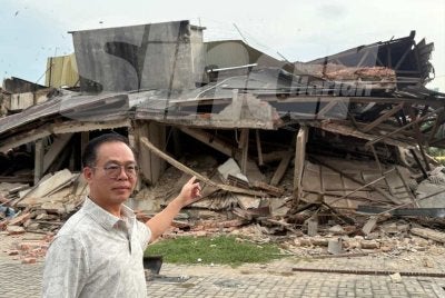Chee Leong menunjukkan bangunan rumah kedai yang runtuh dalam kejadian Sabtu