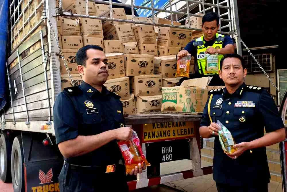 Aswadi (kanan) bersama pegawai KPDN Kelantan menunjukkan minyak masak peket yang berjaya dirampas semasa sidang akhbar pada Ahad.