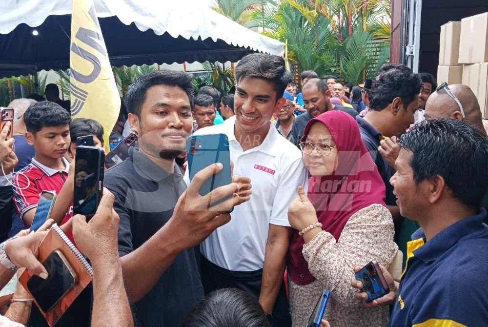 Syed Saddiq (tengah) bergambar dengan penduduk Muar yang menunggu di Pusat Khidmat Ahli Parlimen Muar.