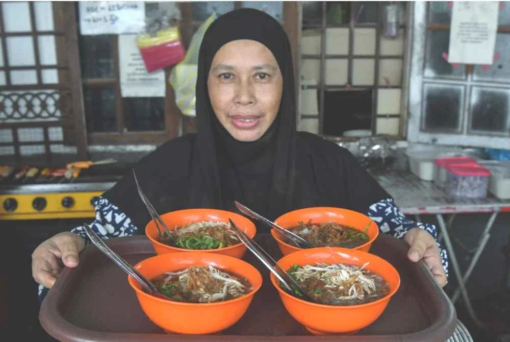Aminah atau mesra disapa Kak Tie menunjukkan aneka mi celup yang dijual ketika ditemui di kedai Kak Tie Mee Celup Dua Amah di Kampung Raja baru-baru ini. Foto Bernama