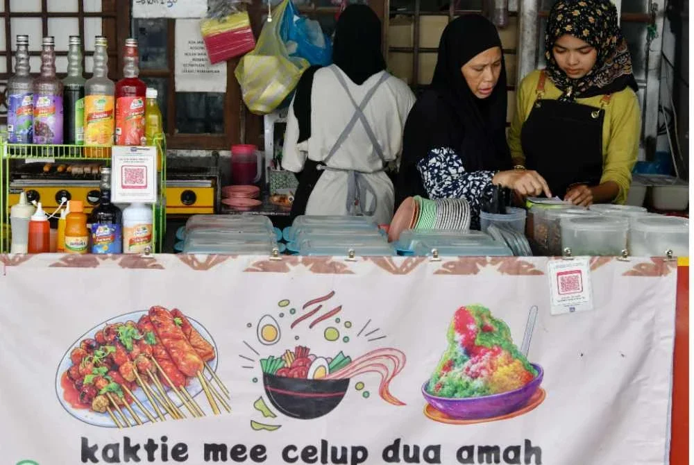 Aminah sibuk menyiapkan mi celup pesanan pelanggan ketika ditemui di kedai Kak Tie Mee Celup Dua Amah di Kampung Raja baru-baru ini. Foto Bernama