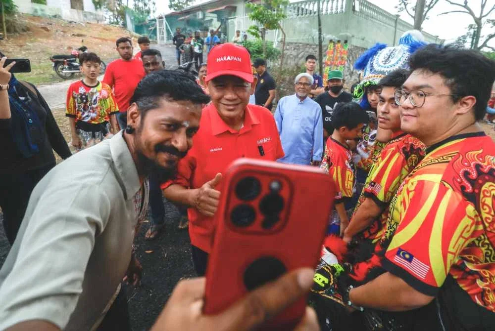 Aminuddin melayan kerenah penduduk setempat untuk berswafoto ketika menghadiri sesi beramah mesra bersama masyarakat India di Pasir Panjang pada Ahad. Foto Bernama