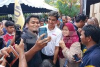 Syed Saddiq (tengah) bergambar dengan penduduk Muar yang menunggu di Pusat Khidmat Ahli Parlimen Muar.