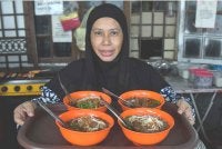 Aminah atau mesra disapa Kak Tie menunjukkan aneka mi celup yang dijual ketika ditemui di kedai Kak Tie Mee Celup Dua Amah di Kampung Raja baru-baru ini. Foto Bernama