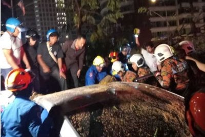 Anggota bomba sedang mengeluarkan mangsa tersepit di dalam kereta akibat dihempap pokok berhampiran Kedutaan Amerika Syarikat di Jalan Tun Razak.