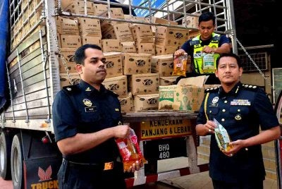 Aswadi (kanan) bersama pegawai KPDN Kelantan menunjukkan minyak masak peket yang berjaya dirampas semasa sidang akhbar pada Ahad.