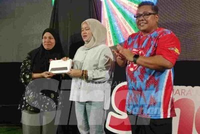 Nor Hadila (kiri) menerima hadiah cabutan bertuah daripada Ketua Pegawai Eksekutif Grup Sinar Karangkraf, Farah Hussamuddin (tengah) dan Ketua Pengarang Kumpulan Sinar Harian, Zamri Rambli dalam program Riuh BOLA SINAR x redOne Mobile x RTM di Restoran Hakim, Seksyen 7, Shah Alam pada Ahad.