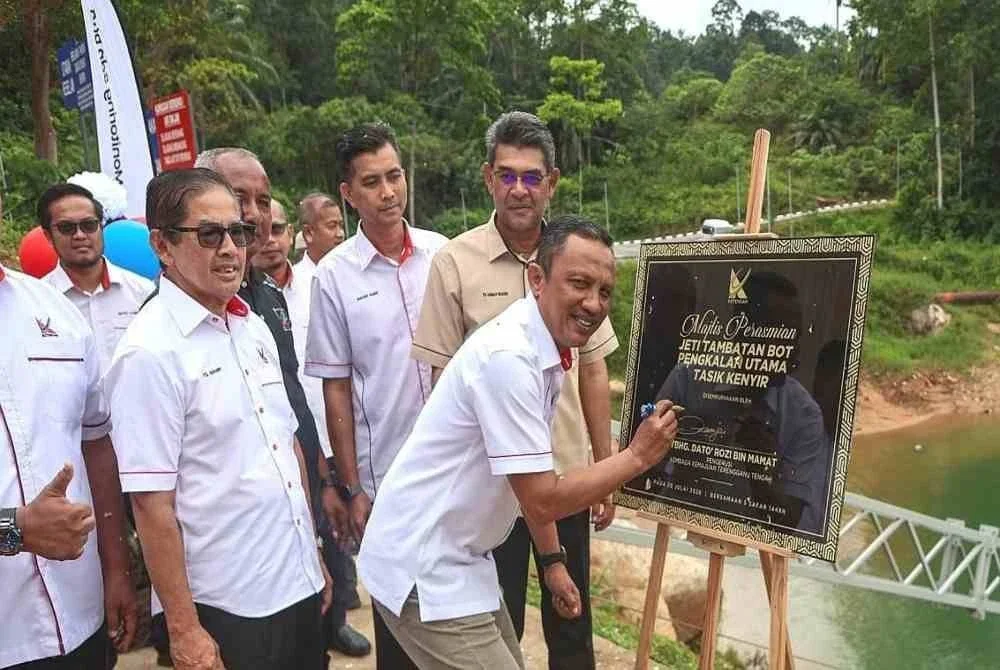 Rozi (kanan) menandatangani plak gimik perasmian Majlis Penyerahan Projek Membina dan Menyiapkan Kerja-Kerja Pengukuhan Tebing serta Kemudahan Berkaitan di Jeti Tambatan Bot Pengkalan Utama, Tasik Kenyir, Hulu Terengganu pada Isnin.