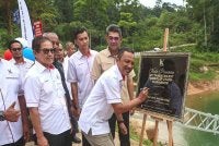 Rozi (kanan) menandatangani plak gimik perasmian Majlis Penyerahan Projek Membina dan Menyiapkan Kerja-Kerja Pengukuhan Tebing serta Kemudahan Berkaitan di Jeti Tambatan Bot Pengkalan Utama, Tasik Kenyir, Hulu Terengganu pada Isnin.