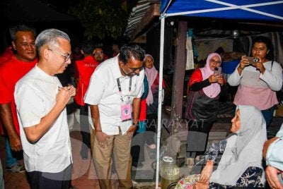 Fahmi (kiri) dan Manivanan (dua kiri) ketika menyantuni sebuah keluarga di Felda Palong 2 pada Isnin.