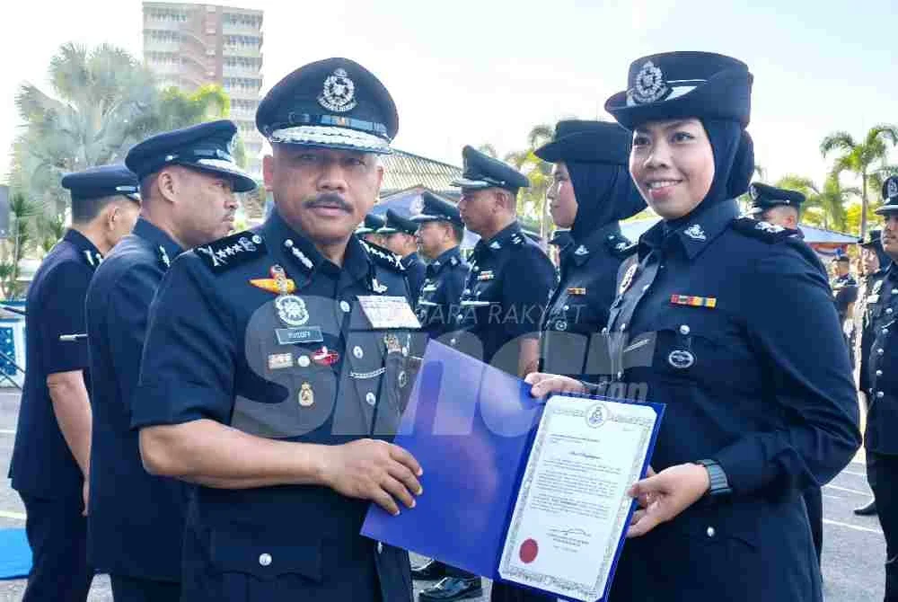 Mohd Yusoff (kiri) menyampaikan surat penghargaan kepada pegawai semasa perhimpunan bulanan di IPK Kelantan pada Selasa.