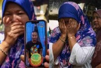 Rozita Ramli, 47, tidak dapat menahan sebak mengenangkan anaknya, Mohd Ilham Che Mat Satar, 27, yang hilang ketika keluar menaiki bot dipercayai untuk memukat ikan di Sungai Galas, Kampung Batu 6, pada pagi semalam. Foto Bernama.