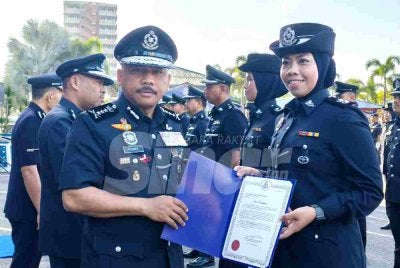 Mohd Yusoff (kiri) menyampaikan surat penghargaan kepada pegawai semasa perhimpunan bulanan di IPK Kelantan pada Selasa. 