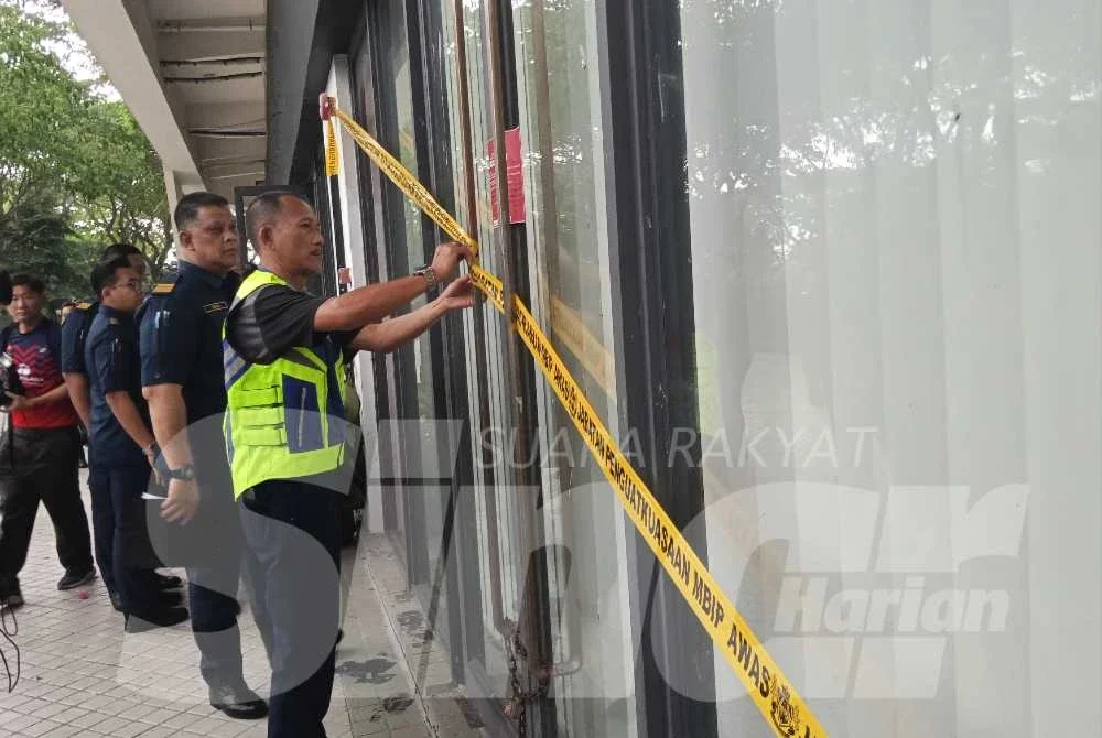 Anggota penguat kuasa MBIP memasang pita kuning di salah satu premis Network School.