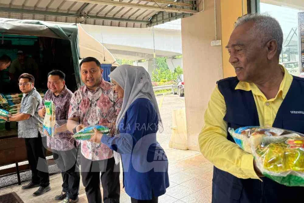 Mohd Ridhwan (tengah) menerima barangan yang diterima daripada rakan penyumbang bagi agihan kit makanan.