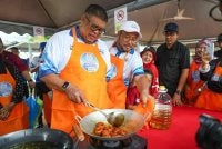 Ab Rauf (kiri) turut memasak kuih keria pada Festival Sungai Melaka.