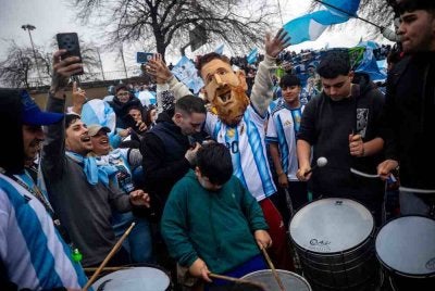 Seorang penyokong memakai topeng yang menggambarkan penyerang Argentina, Lionel Messi, berhampiran kem latihan Persatuan Bola Sepak Argentina (AFA) di Ezeiza, Wilayah Buenos Aires, pada 20 Julai 2026, ketika menunggu ketibaan pasukan bola sepak kebangsaan Argentina dari Amerika Syarikat selepas kekalahan mereka dalam perlawanan akhir Piala Dunia FIFA 2026.
