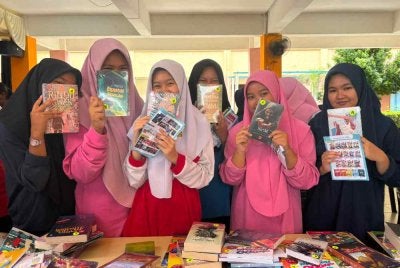 Pelajar SMK Bidor menunjukkan buku-buku yang dibeli menerusi penebusan Baucar Buku Madani. 