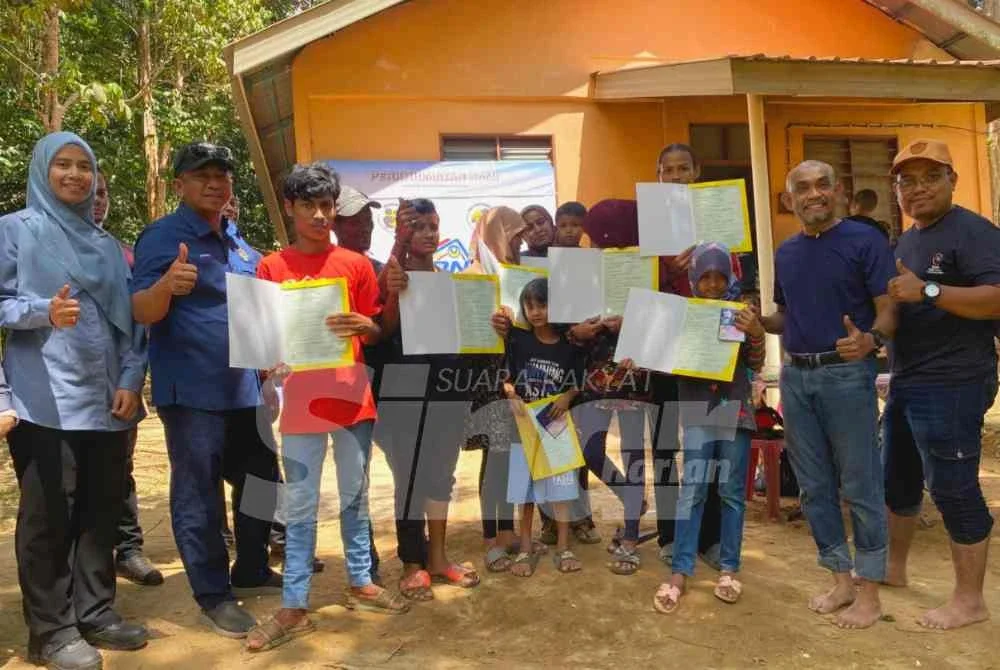 Badrul Hisham (dua dari kiri) semasa menyerahkan sijil kelahiran kepada lapan anak Zapni di Kampung Johal, Kuala Krai sempena Program Menyemai Kasih Rakyat (Mekar).