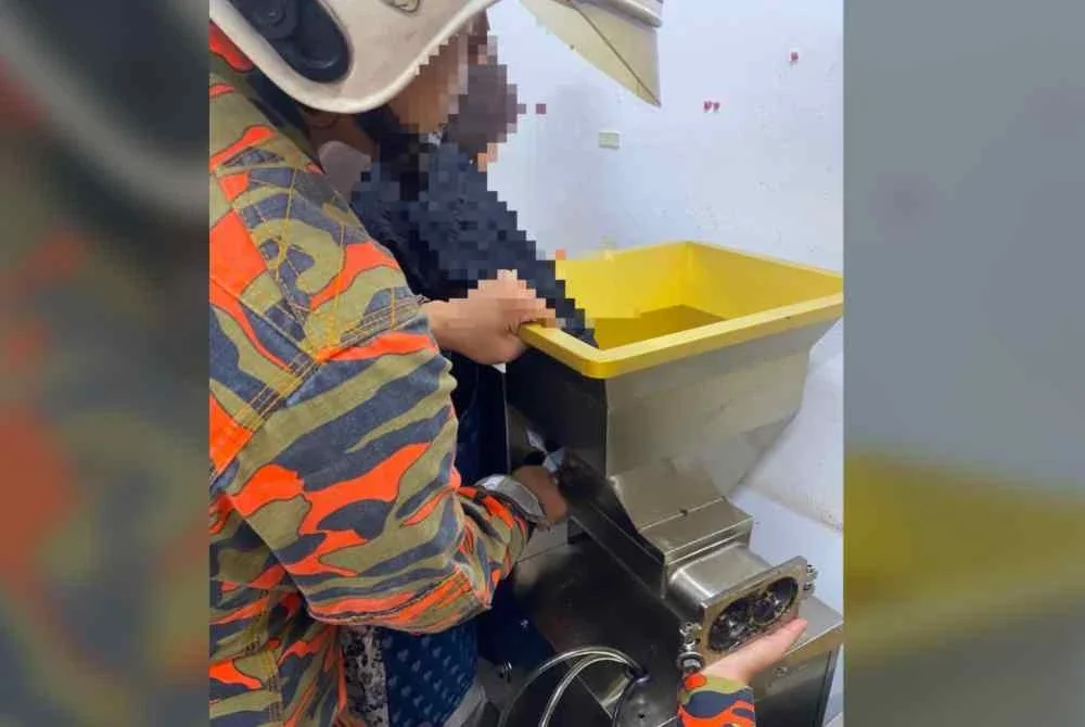 Mangsa menahan sakit selepas jarinya tersepit di mesin kuih dalam kejadian di rumah nya pada Khamis. Foto JBPM Melaka