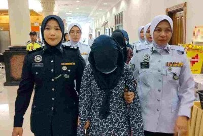 Nur Liana (depan) bersama dua remaja perempuan bawah umur diiringi anggota polis ketika dibawa untuk dituduh di Mahkamah Majistret Khas Trafik di Kuantan pada Khamis.