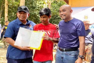 Badrul Hisham (kiri) menyerahkan sijil kelahiran kepada penerima di Kampung Johal, Kuala Krai sempena Program Menyemai Kasih Rakyat (Mekar), pada Khamis.
