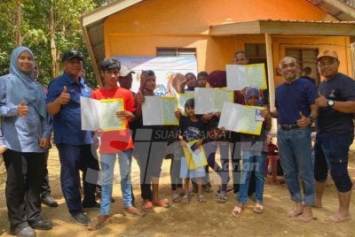 Badrul Hisham (dua dari kiri) semasa menyerahkan sijil kelahiran kepada lapan anak Zapni di Kampung Johal, Kuala Krai sempena Program Menyemai Kasih Rakyat (Mekar).