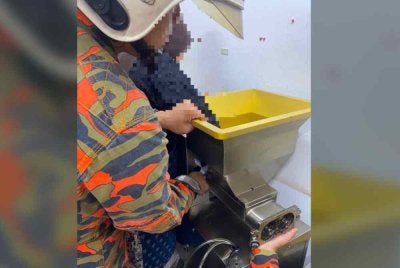 Mangsa menahan sakit selepas jarinya tersepit di mesin kuih dalam kejadian di rumah nya pada Khamis. Foto JBPM Melaka