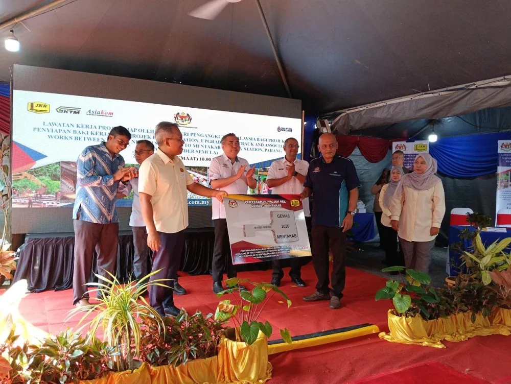 Anthony Loke (tengah) ketika menyaksiakan simbolik penyerahan kunci sebagai kerja siap projek berkenaan di KTMB Bahau pada Jumaat.
