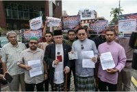 Mohd Azmi (tengah) menunjukkan memorandum bantahan berhubung tekanan yang diberikan oleh ahli Kongres AS ke atas dasar kedaulatan Malaysia di hadapan Kedutaan AS di sini, hari ini. - Foto: Bernama
