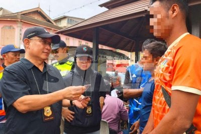 Garry Belayong (kiri) dan pegawai bertugas memeriksa kad UNHCR yang dipercayai palsu semasa Ops Mega di sekitar Bandar Kota Bharu pada Jumaat. Foto: HAZELEN LIANA KAMARUDIN