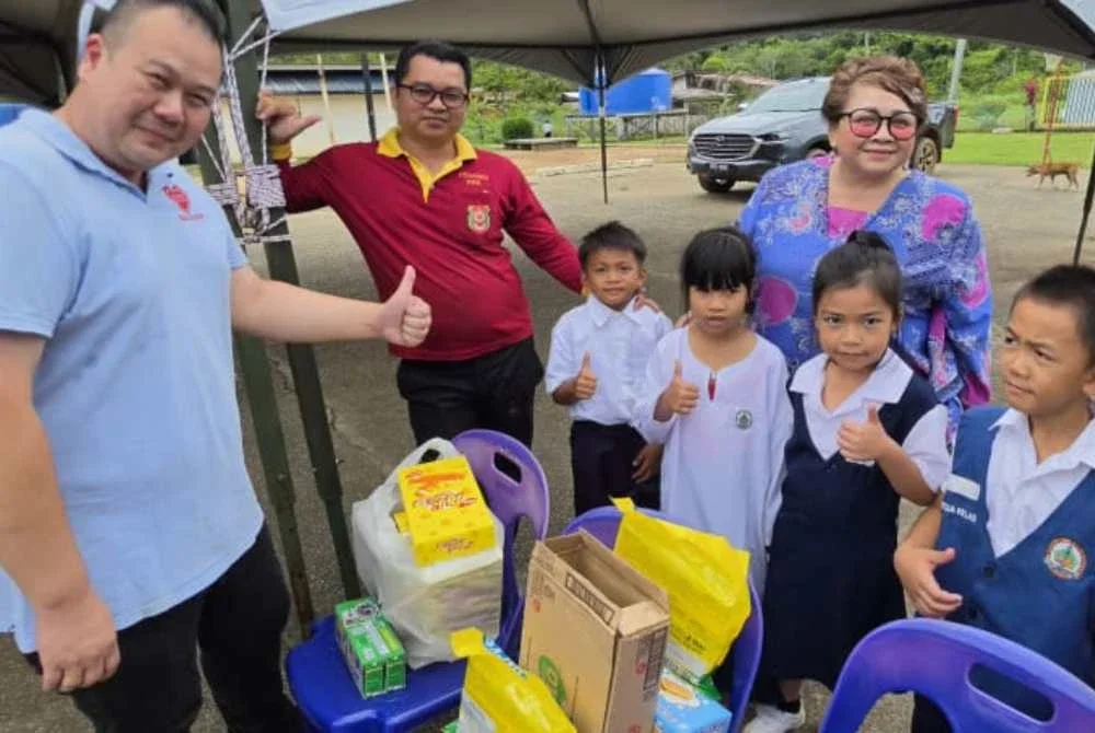 Chun Tak (kiri) mengagihkan buah tangan untuk murid-murid.