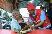 Aminuddin (kanan) menyantuni orang ramai ketika berkempen di Warung Sulaiman pada Sabtu. Foto Bernama