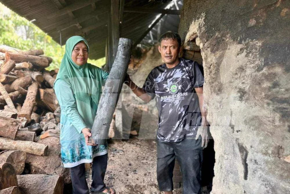 Pazuriatiayu (kiri) dan pekerja mengangkat kayu arang. Foto: ADILA SHARINNI WAHID
