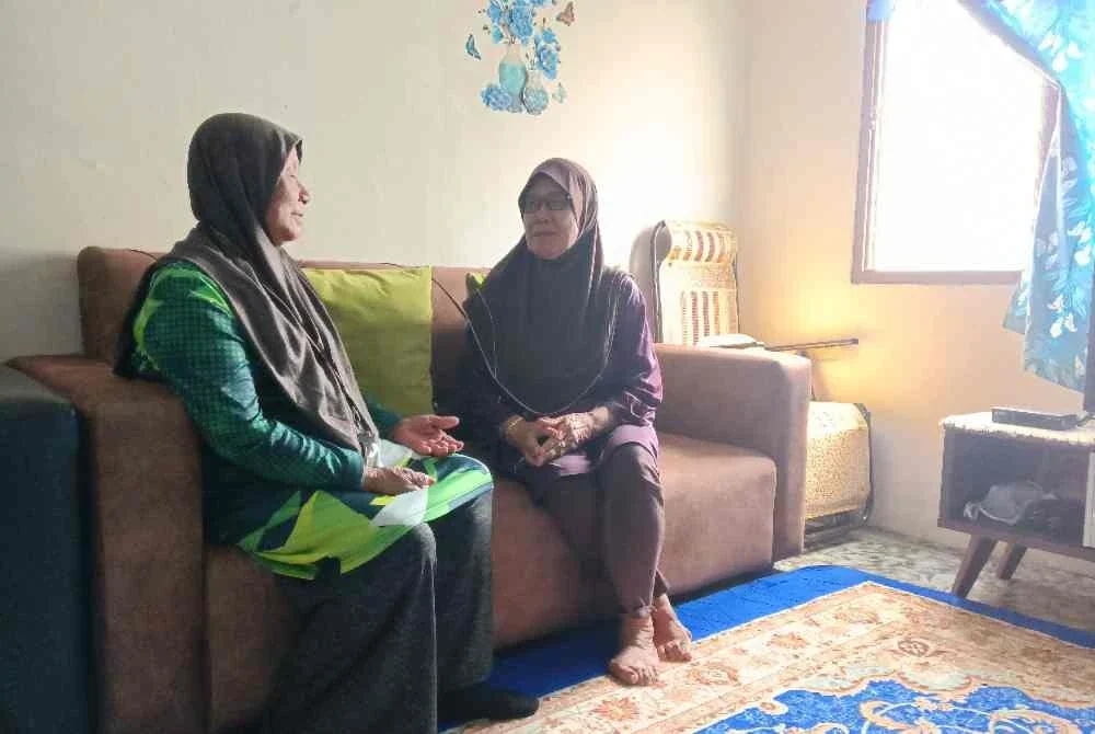 Seorang penduduk, Rafiah Mat Din (kanan) berbual dengan jiran, Salasiah Shaari (kiri) di kediamannya di PPR Lembah Subang 1.